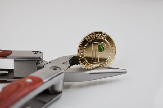 Digital currency physical gold peercoin coin and pocket knife on the table.