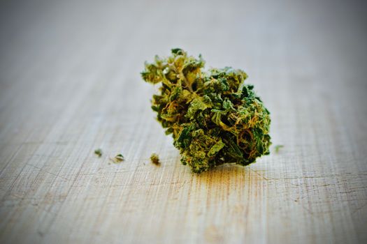 Green marijuana dry leafs on wooden board.