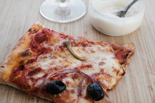 White garlic sauce and slice of delicious pizza on the wooden board.