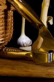 Garlic press and cloves of garlic laid on a wooden table background