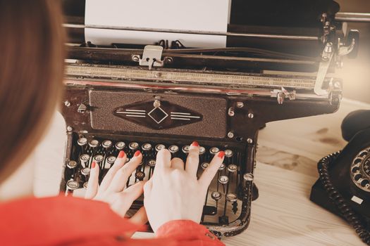 Secretary at old typewriter with telephone. Young woman using typewriter. Business concepts. Retro picture style.