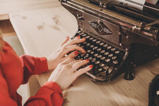 Secretary at old typewriter with telephone. Young woman using typewriter. Business concepts. Retro picture style.