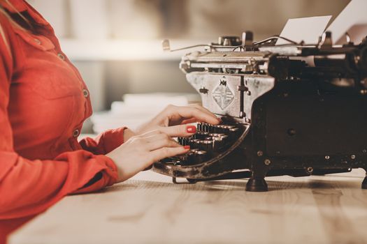 Secretary at old typewriter with telephone. Young woman using typewriter. Business concepts. Retro picture style.