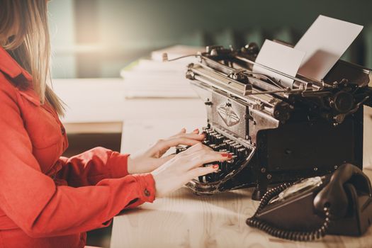 Secretary at old typewriter with telephone. Young woman using typewriter. Business concepts. Retro picture style.