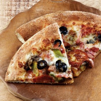 Two Slices of Freshly Baked Pepperoni Pizza with Black Olives, Ham and Cheese on Rustic Wooden background