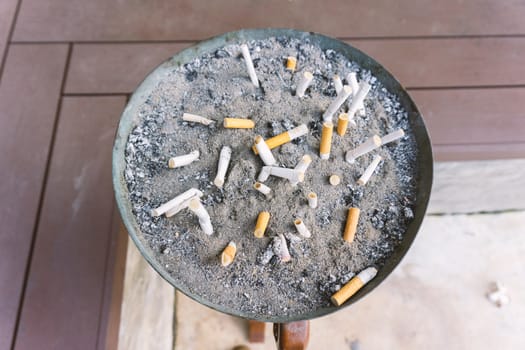 Cigarette in outdoors ashtray with sand closeup , process with vintage style.