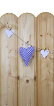 Three hearts with clothes pegs on a cord on wood