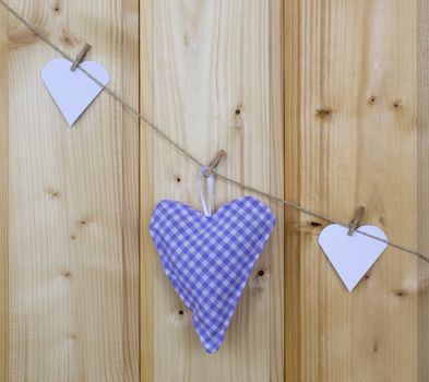 Three hearts with clothes pegs on a cord on wood