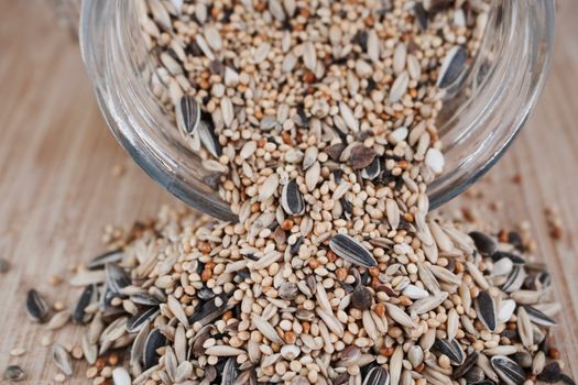 Fresh seeds in big glass jar on the wooden board in the kitchen. Abstract concept.