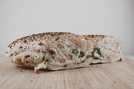 Delicious sandwich with seeds bread, tuna, salad and vegetables on the wooden board.