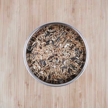 Fresh and healthy seeds in metal chrome container on the wooden board in the kitchen.