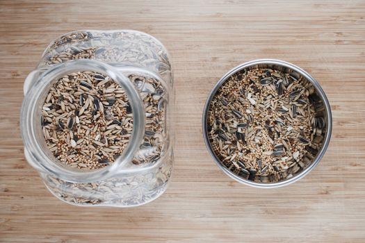 Tasty and fresh seeds in the glass jar and metal container on the wooden board.