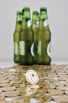Digital currency physical gold peercoin coin near green beer bottles on the money.