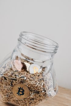 Digital currency physical gold bitcoin coin in jar with silver bitcoins.