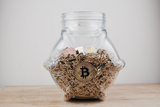 Cryptocurrency physical gold silver and brass bitcoins in glass jar on the wooden table.