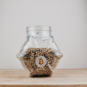 Digital currency physical silver bitcoin coin in jar with fresh seeds.