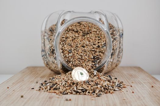 Digital currency physical gold peercoin coin in seeds and glass jar.