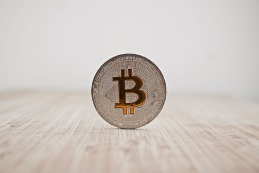 Cryptocurrency physical silver bitcoin coin on the wooden board.