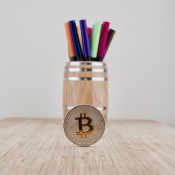 Digital currency physical silver bitcoin coin near wooden barrel.