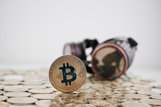 Digital currency physical gold bitcoin coin on the money near steampunk glasses.