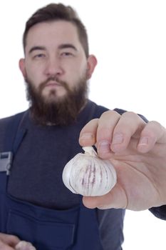 head of garlic in the hand of a young bearded farmer