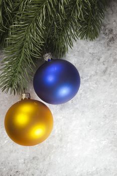 Multicolored balls and fir branch on snow
