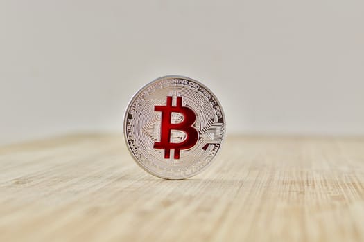 Cryptocurrency physical silver bitcoin coin with red sign on the wooden board.