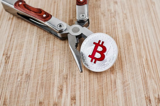 Digital currency physical red bitcoin coin on the wooden board. Pocket Knife.