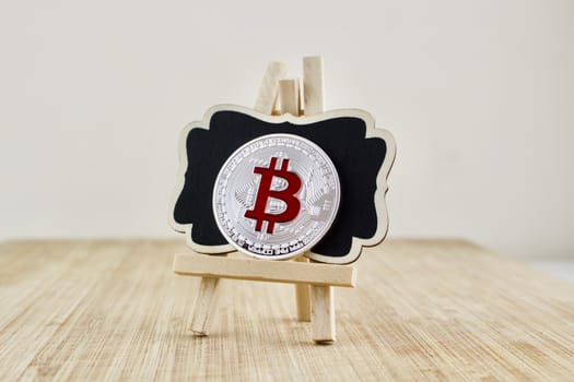 Digital currency physical red bitcoin coin on the wooden stand.
