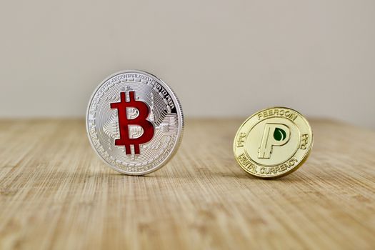 Digital currency physical silver bitcoin coin and gold peercoin on the wooden board.
