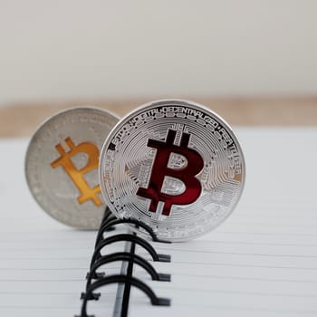 Digital currency physical silver yellow and red bitcoin coins in notebook.
