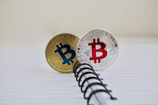 Digital currency physical gold and silver bitcoins in notebook on the table.