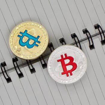 Digital currency physical gold and blue bitcoin near silver red coin.