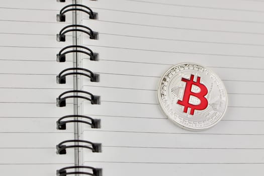 Digital currency physical red bitcoin coin in notebook. Business concept.