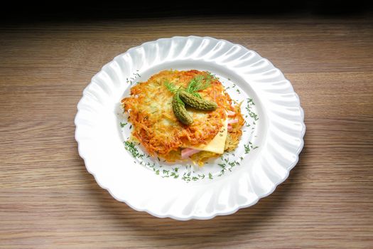 Potato pancake burger with ham and cheese. On a wooden background