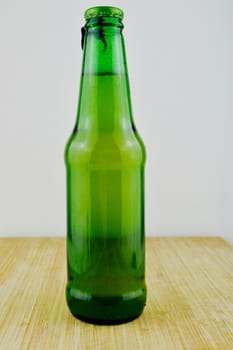 Fresh and tasty beer in glass green small bottle on the wooden board.