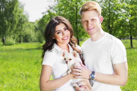 Happy smiling young couple with their dog in park