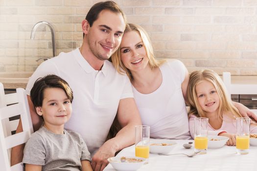 Happy family having breakfast with corn flakes and juice