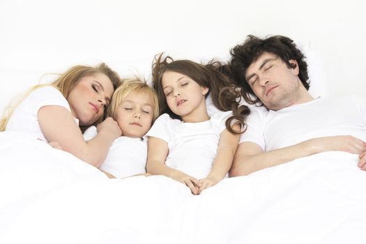 Cute family sleeping together in the parents's bed