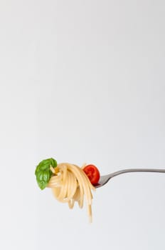 fork with italian pasta. Basil, spaghetti and tomato. White background.