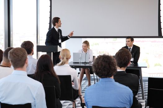 Speaker at business conference near white screen and audience