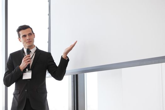 Businessman giving a presentation on blank white board with copy space