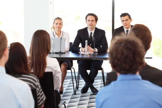 Group of speakers at business meeting at the table with microphones