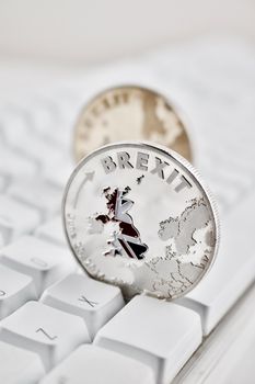 Europe leaving. Brexit physical coin on the white keyboard. British map.