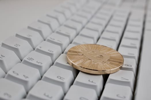 Digital currency physical gold bitcoin coin on white computer keyboard.