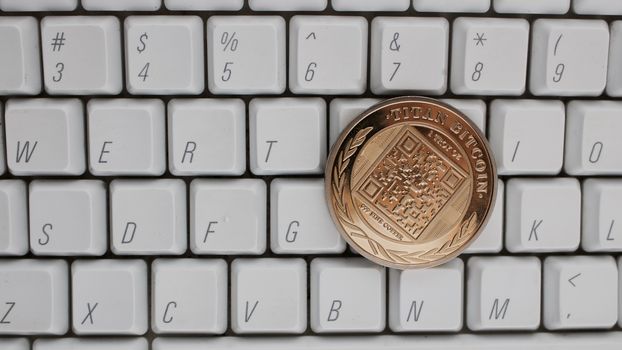 Digital currency physical gold titan bitcoin on white computer keyboard.