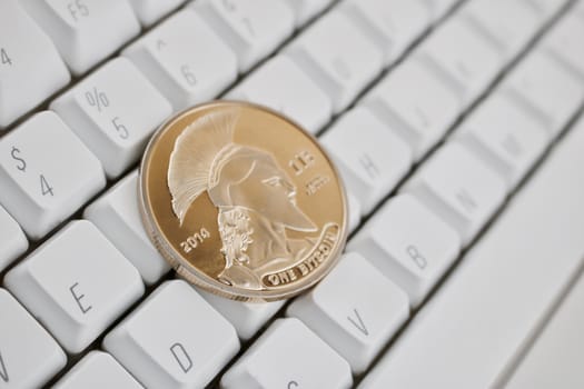 Digital currency physical gold titan bitcoin on white computer keyboard.
