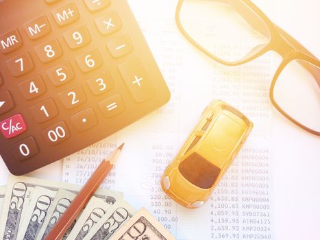 Business, finance, savings, banking or car loan concept : Miniature car model, pencil, calculator, eyeglasses, money and savings account passbook or financial statement on white background