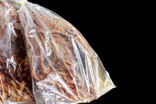 Dried fish in plastic bag with black background.