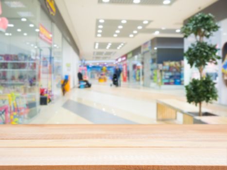 Light wooden board empty table in front of blurred shopping mall - can be used for display or montage your products. Mockup for display of product.